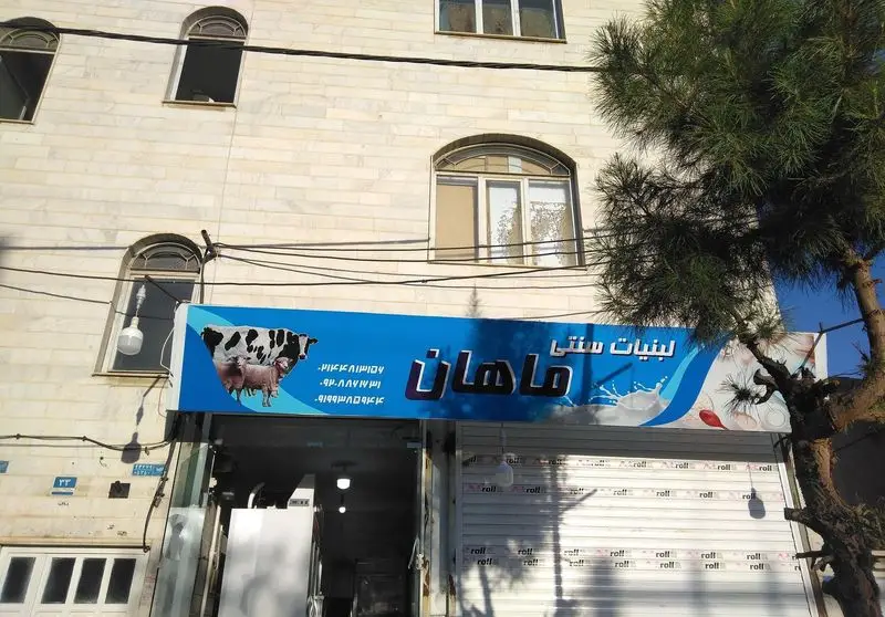 تابلوی آبی رنگ فروشگاه لبنیات سنتی ماهان در یزد، با تصویر گاو، گوسفند و نشان شیر تازه، برای معرفی محصولات لبنی محلی.