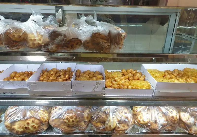 نمایش ویترین قنادی فرح بخش با انواع نان‌های سنتی بسته‌بندی شده و شیرینی‌های تازه و آبدار مانند بامیه و زولبیا.