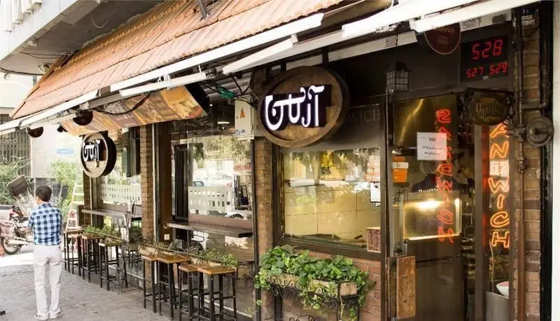 نمای بیرونی جذاب فست فود مجموعه آرمن با تابلوی روشن ساندویچ و فضای باز نشیمن، آماده استقبال از مشتریان است.