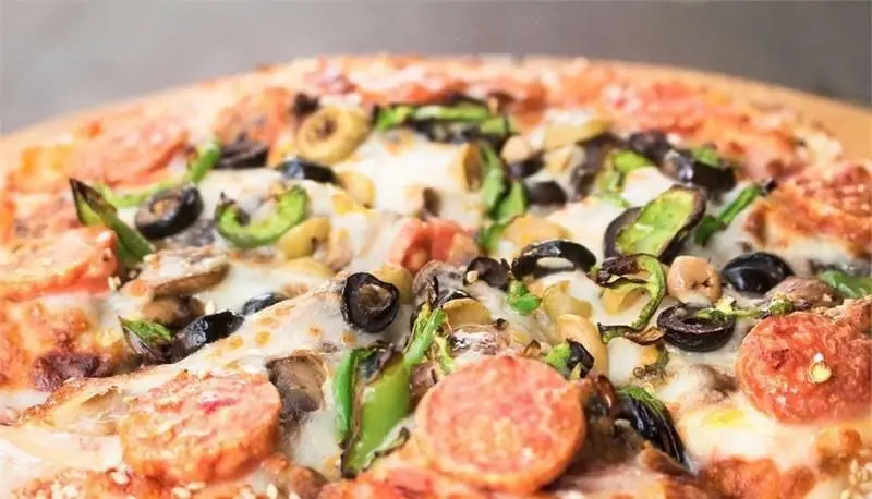 نمای نزدیک پیتزا ویژه و خوش طعم فست فود مجموعه آرمن با تاپینگ های متنوع پپرونی، قارچ، زیتون و فلفل سبز، یک غذای محبوب و باکیفیت.