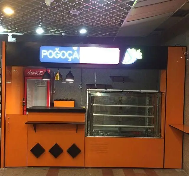 تصویر دکه فست فود پوآچا با طراحی مدرن و رنگ نارنجی چشم‌نواز، شامل یخچال نوشیدنی کوکا کولا و ویترین نمایش محصولات تازه.