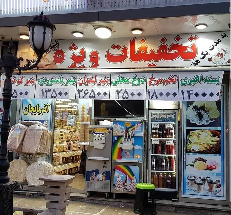 نمای فروشگاه لبنیات سنتی آذربایجان با بنر تخفیفات ویژه بر روی پنیر، دوغ، پسته و بستنی؛ شامل محصولات محلی و نان سنتی.