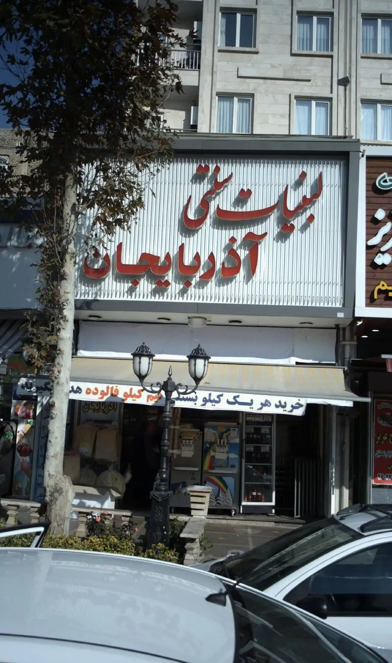 نمای خارجی لبنیات سنتی آذربایجان با تابلوی قرمز و سفید، ارائه دهنده محصولات لبنی محلی و بستنی سنتی برای تجربه خرید دلپذیر.