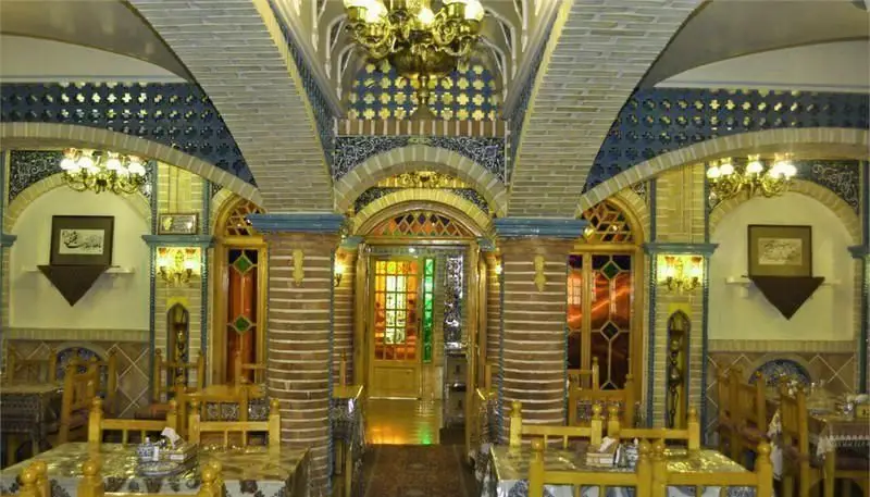 فضای داخلی سفره خانه سنتی باربد: معماری اصیل ایرانی با سقف‌های طاق‌دار آجری، کاشی‌کاری‌های چشم‌نواز و پنجره‌های رنگارنگ سنتی.