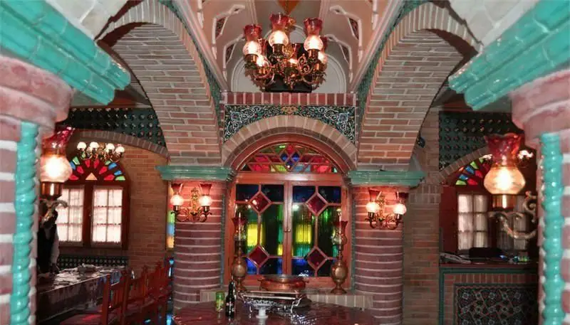 نمایی از فضای داخلی جذاب سفره خانه سنتی باربد با معماری اصیل ایرانی، طاق‌ها، پنجره‌های ارسی رنگارنگ و دکوراسیون سنتی دلنشین