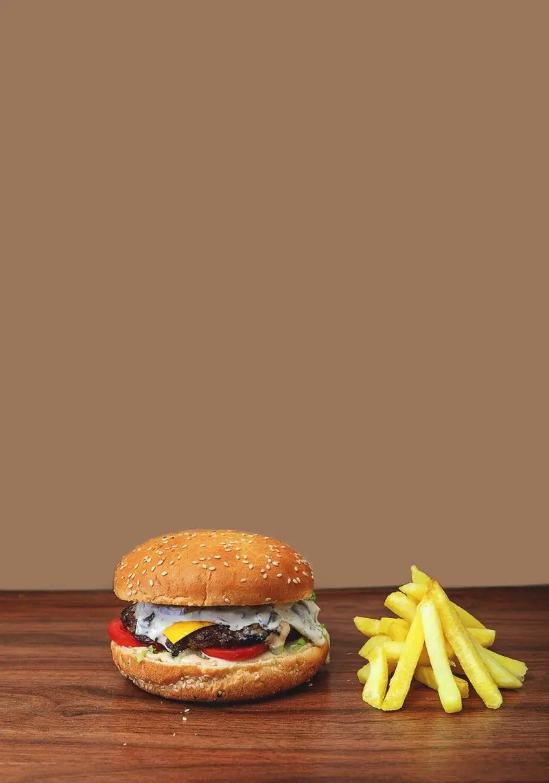 تصویر وسوسه‌انگیز همبرگر ویژه آمی چی: نان کنجدی، برگر گوشت، پنیر، گوجه، سس مخصوص و سیب‌زمینی سرخ‌کرده طلایی از پیتزا آمی‌چی.