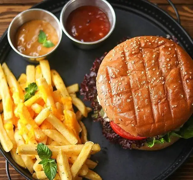 عکس منو کافه ریکو: همبرگر لذیذ با نان کنجدی گریل شده، کاهو، گوجه و برگ‌های بنفش، سیب زمینی سرخ کرده پنیری و دو سس.