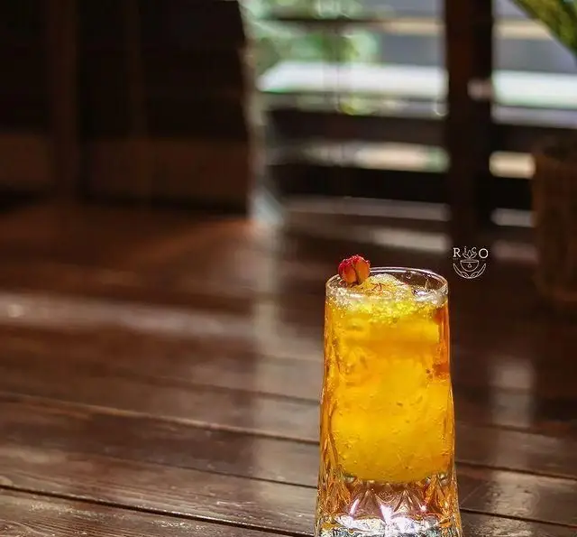 نوشیدنی خنک و دلپذیر کافه ریکو، با تزئین زعفرانی و میوه‌ای روی میز چوبی. مناسب برای تجربه ای شیک و تابستانی در محیط دنج کافه.