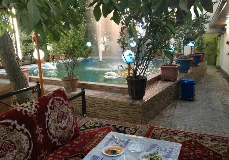 باغچه رستوران ساحل، محیطی دلپذیر و سنتی با حوض زیبا، فواره و قوهای سفید، ایده‌آل برای صرف غذا در فضای باز و آرامش‌بخش.