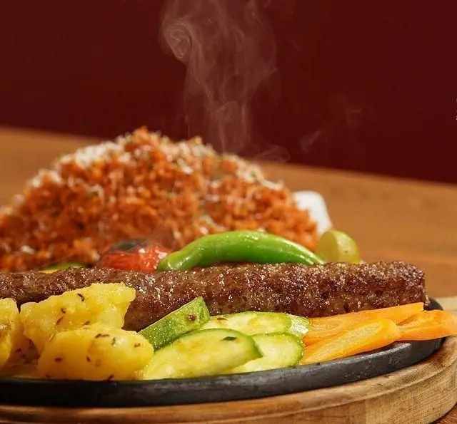 کباب داغ و لذیذ کافه رستوران زیرزمین، شامل دو سیخ کباب کوبیده با پلو، سیب‌زمینی و سبزیجات تازه. تجربه‌ای بی‌نظیر از غذای ایرانی.