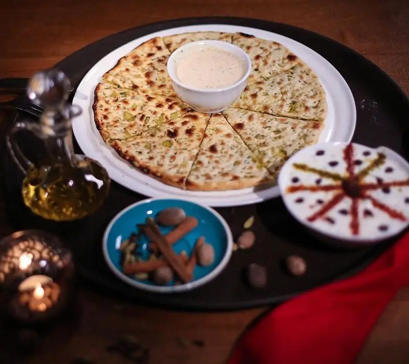 تصویری جذاب از نان سیر و پیازچه با دیپ ویژه، ماست و چاشنی‌های اصیل ایرانی در کافه رستوران زیرزمین. غذایی لذت‌بخش.