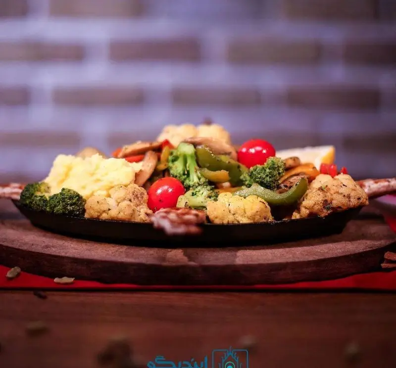 وعده غذایی سالم کافه رستوران زیرزمین: بشقاب داغ شامل مرغ گریل، پوره سیب‌زمینی، بروکلی، گل‌کلم، فلفل دلمه‌ای و گوجه.