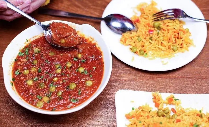 غذای خوش‌رنگ و خوش‌طعم کافه رستوران زیرزمین: خوراک گوجه فرنگی و نخودفرنگی در کنار برنج سبزیجات زرد معطر و لذیذ.