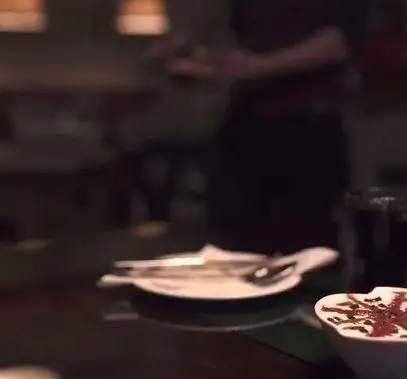 صحنه ای از کافه رستوران زیرزمین: میزی با بشقاب، قاشق و چنگال و دسر خوشرنگ، و پرسنلی در حال فعالیت در محیطی آرام و دلپذیر.