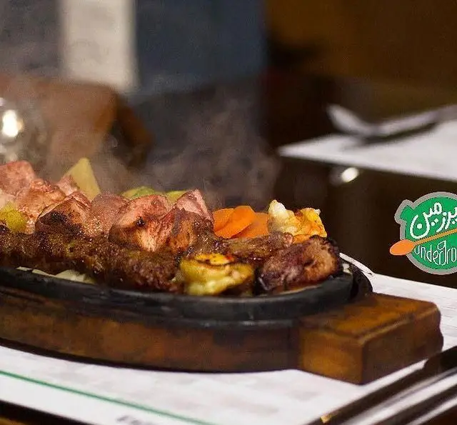 سینی کباب و گوشت داغ و خوشمزه از کافه رستوران زیرزمین، غذای اصیل ایرانی با سبزیجات تازه، تجربه‌ای لذیذ و دلپذیر.