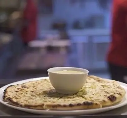 نان تازه و معطر با پنیر یا سبزیجات، همراه با سس مخصوص، آماده در کافه رستوران زیرزمین. ایده‌آل برای صبحانه یا لذت یک میان‌وعده.