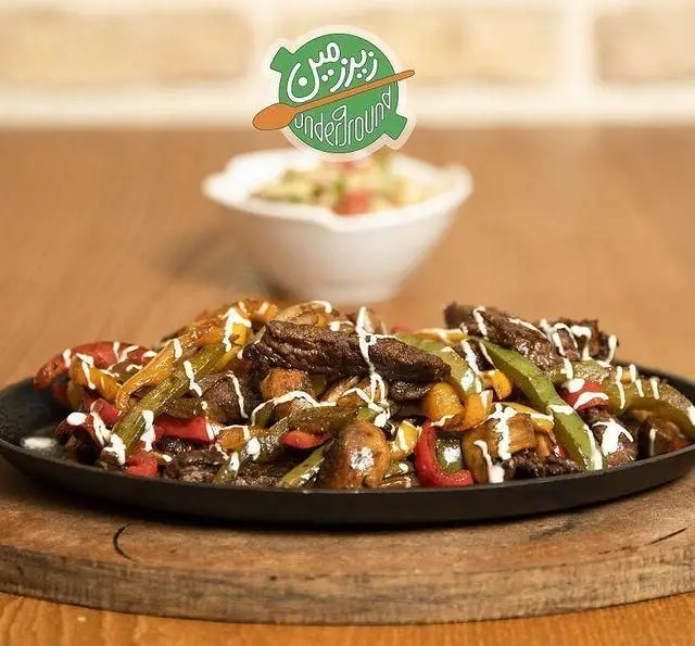 بشقاب داغ و خوشمزه بیف استیک و سبزیجات فاهیتا، شامل فلفل دلمه ای رنگی و قارچ، با سس سفید مخصوص کافه رستوران زیرزمین.