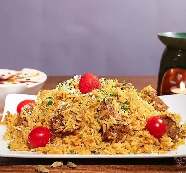 بریانی گوشت ویژه کافه رستوران زیرزمین، با عطر دلپذیر برنج و ادویه‌جات تازه، تزیین شده با گوجه و سبزیجات، یک وعده غذایی عالی.