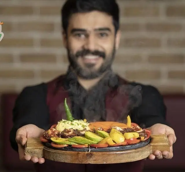 تجربه دلنشین در کافه رستوران زیرزمین؛ سرآشپز با لبخند بشقاب داغ و لذیذی از کباب، پوره و سبزیجات تازه را سرو می‌کند.