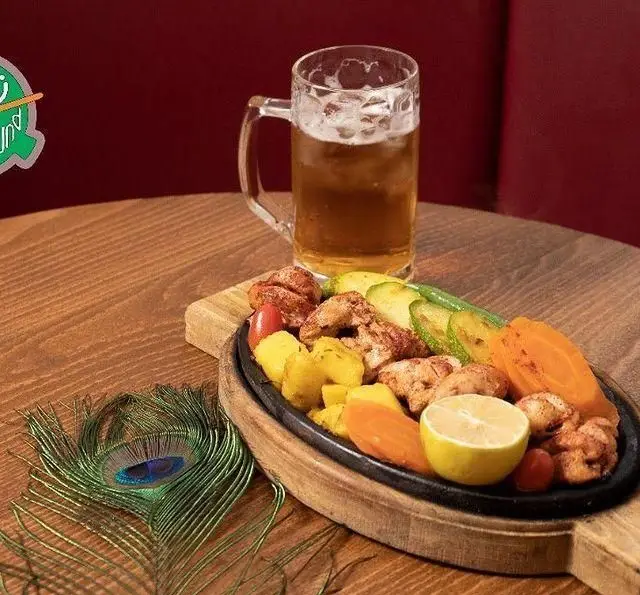 بشقاب داغ و لذیذ مرغ، سیب زمینی و سبزیجات تازه کافه رستوران زیرزمین، با نوشیدنی خنک روی میز چوبی. تجربه‌ای به‌یادماندنی.