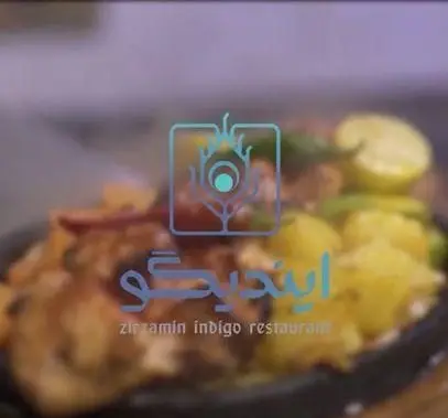تصویر غذای اصلی کافه رستوران زیرزمین ایندیگو: سینی داغ مرغ و سیب‌زمینی با لیمو، همراه لوگو پرطاووسی. بهترین رستوران ایرانی.