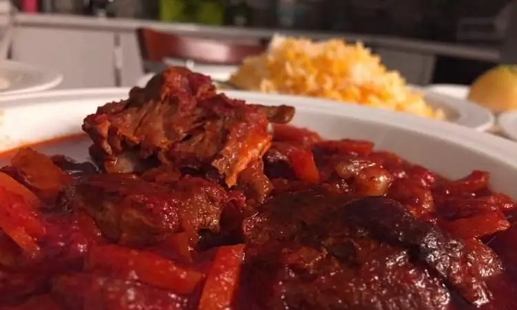 تصویری از خورش گوشت قرمز لذیذ رستوران سنتی دیزی میزی، سرو شده با برنج زعفرانی خوش عطر، یک غذای اصیل ایرانی.