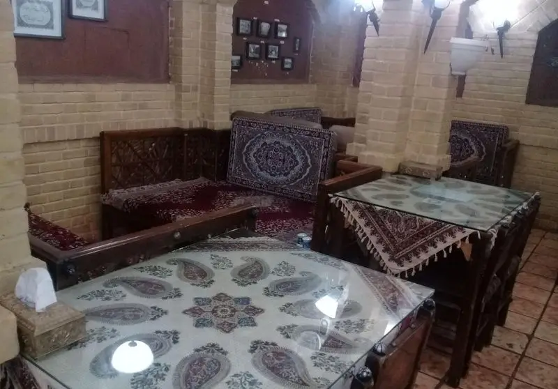 فضای داخلی سنتی و دلنشین رستوران خان باجی با دکوراسیون ایرانی، میزهای چوبی و مبلمان سنتی با فرش و کوسن‌های طرح‌دار