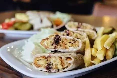 بشقابی از ساندویچ‌های فلافل پیچیده و سیب‌زمینی سرخ کرده با سس و کاهو، غذایی لذیذ در رستوران دمشق الاصیله.