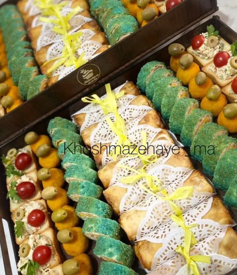 سینی فینگرفود و شیرینی‌های مجلسی از "کیک و شیرینی خوشمزه های ما"؛ شامل رول‌های سبز، شیرینی‌های پاپیون‌دار و مزه‌های شیک.