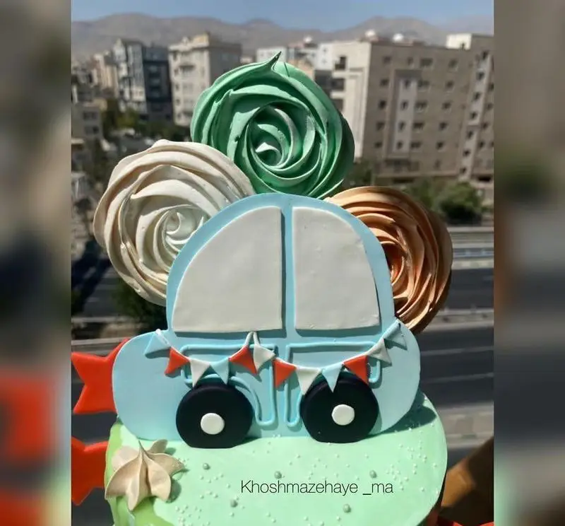 کیک تولد پسرانه فوندانت طرح ماشین آبی با تزئین مرنگ گلدار، مناسب جشن و مهمانی، از کیک وشیرینی خوشمزه های ما.