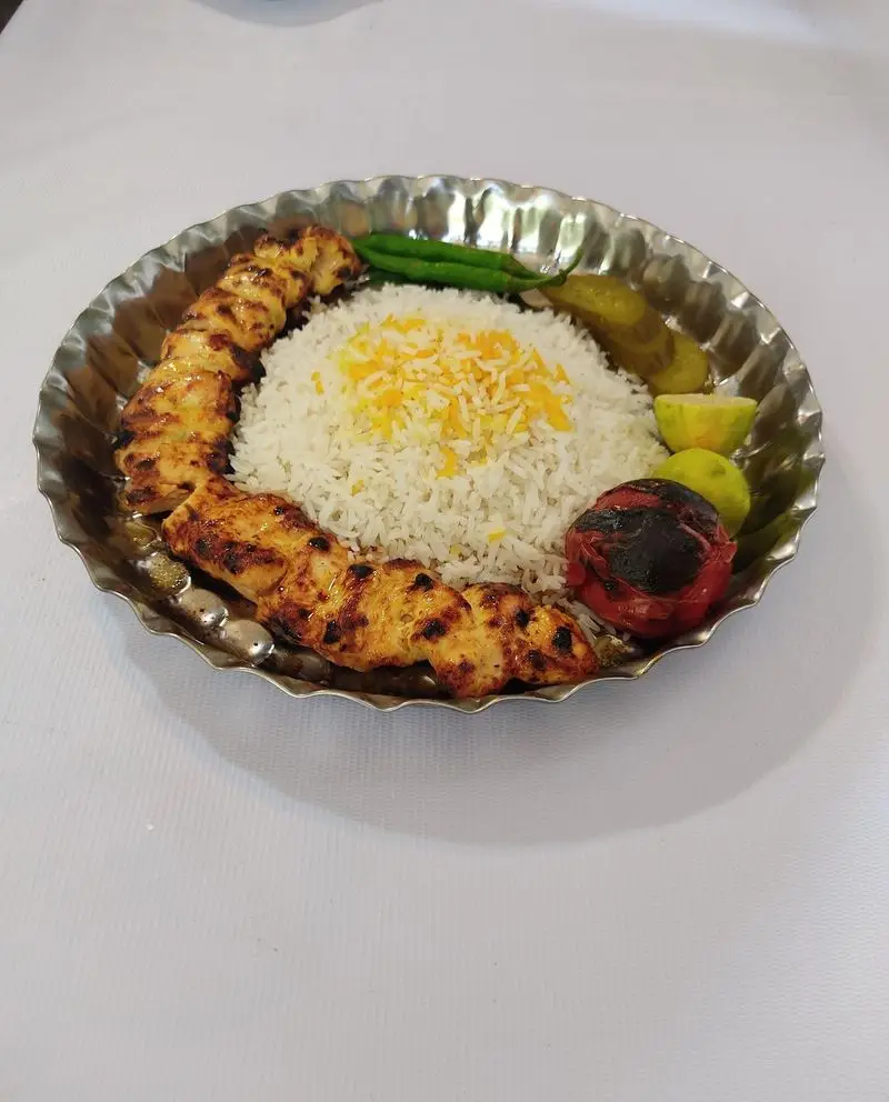 سینی غذای ایرانی شامل جوجه کباب زعفرانی خوش‌رنگ و لذیذ، برنج اعلا، گوجه کبابی، فلفل و لیمو از منوی کترینگ لوتوس.