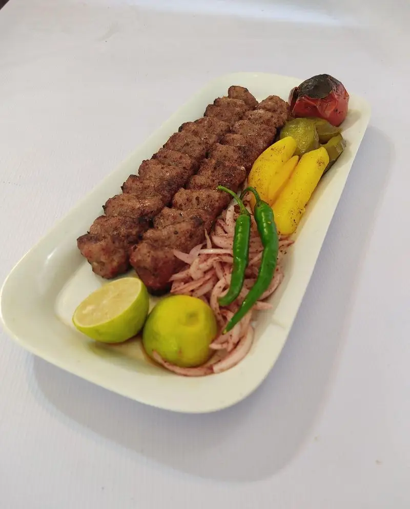 کباب کوبیده مجلسی کترینگ لوتوس، غذای اصیل ایرانی با طعم بی‌نظیر. سرو شده با پیاز، فلفل سبز، لیمو تازه و گوجه کبابی، انتخابی عالی برای وعده غذایی شما.