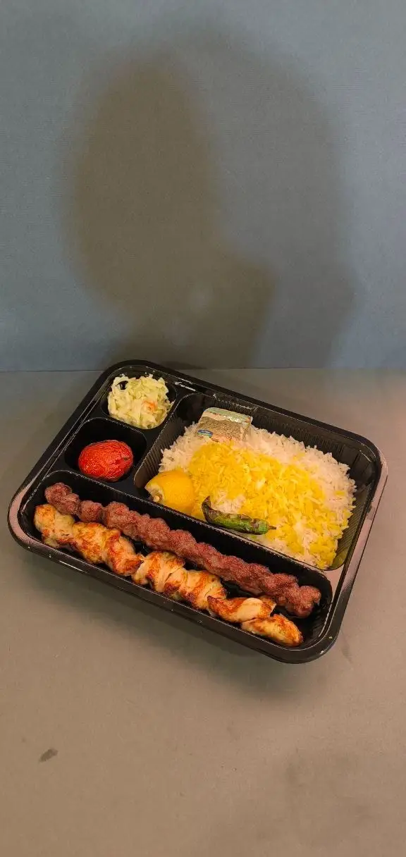 سینی غذای بیرون‌بر کترینگ لوتوس: چلو کباب مخلوط شامل کوبیده و جوجه، برنج زعفرانی، گوجه کبابی، لیمو و سالاد کلم تازه.