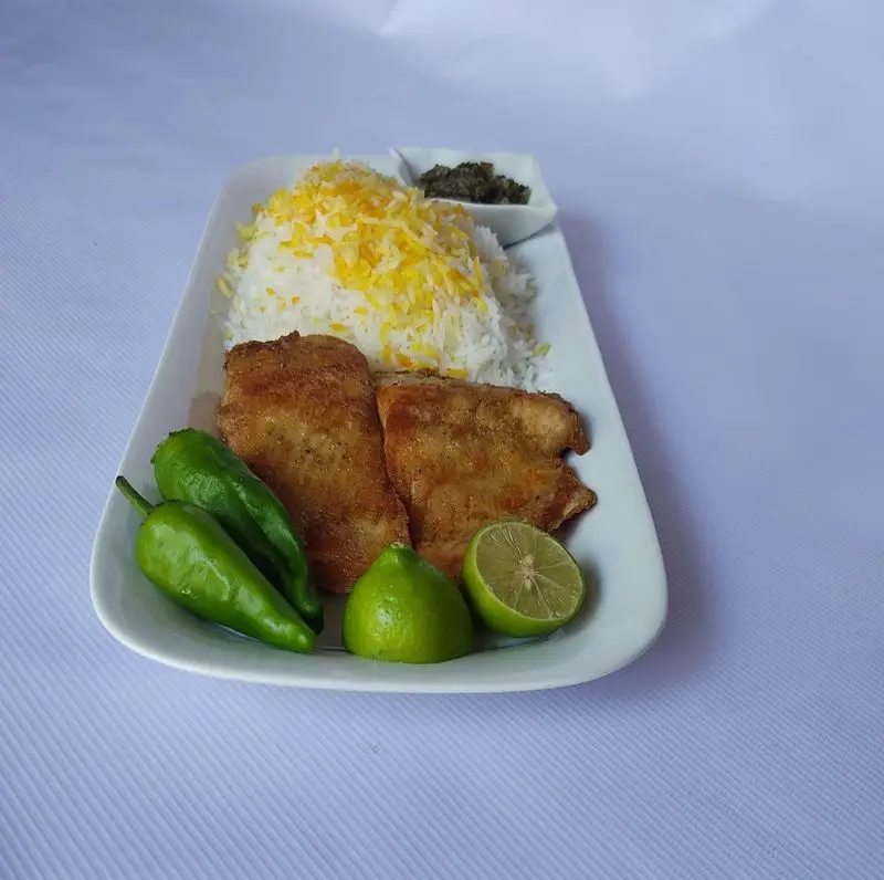 پلو ماهی لذیذ کترینگ لوتوس، غذای خانگی و اصیل ایرانی با ماهی سرخ شده، برنج زعفرانی، فلفل و لیمو تازه. سفارش آنلاین غذا.