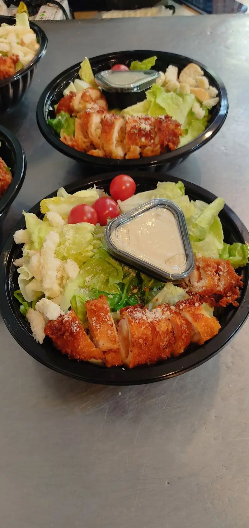 سالاد سزار کترینگ لوتوس شامل کاهو، مرغ سوخاری کریسپی، پنیر پارمزان، گوجه و سس، در ظروف آماده ارسال به مشتریان.