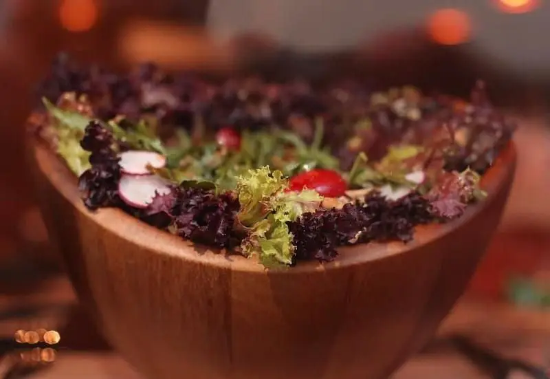 یک کاسه سالاد مجلل و رنگارنگ با کاهو سبز و بنفش، تربچه و گوجه‌فرنگی، آماده سرو در محیط دلنشین رستوران پرزو، تجربه غذای ایتالیایی.