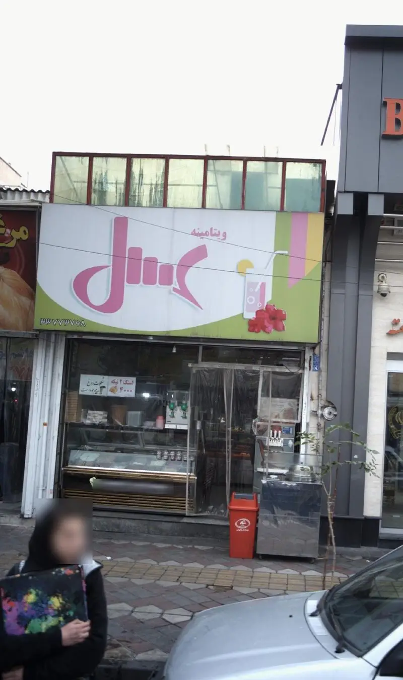 نمای بیرونی فروشگاه ویتامینه عسل، مکانی برای خرید آبمیوه تازه، انواع معجون و بستنی. تابلوی شاخص با طرح نوشیدنی و تلفن ۳۳۷۷۷۷۶۸.