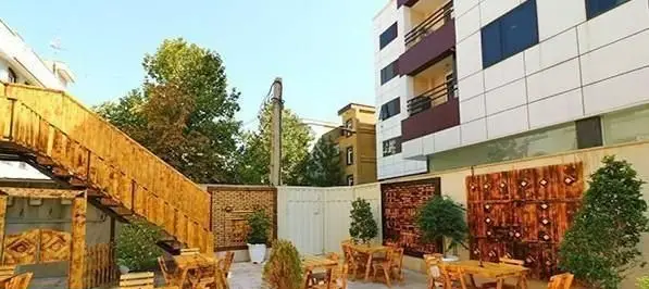 فضای باز و دلنشین پیتزایی ایران ویچ با میز و صندلی‌های چوبی، پله چوبی بلند و تزئینات دیواری منحصربفرد.