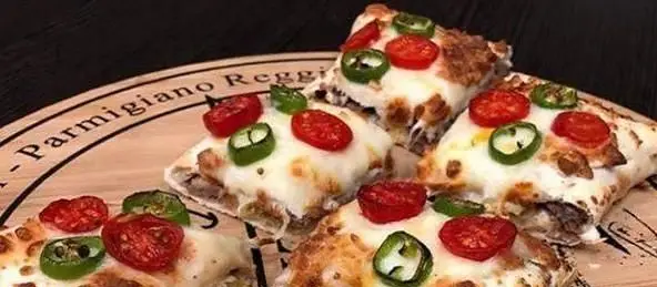 برش‌های پیتزا ایران ویچ با پنیر فراوان، گوجه گیلاسی و فلفل هالوپینو، آماده برای لذت یک غذای خوشمزه و ایتالیایی.