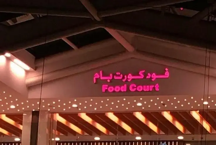 ورودی فود کورت بام با تابلوهای نئون درخشان، میزبان رستوران فرنگی بامیکا لانژ برای تجربه غذایی لذت‌بخش.