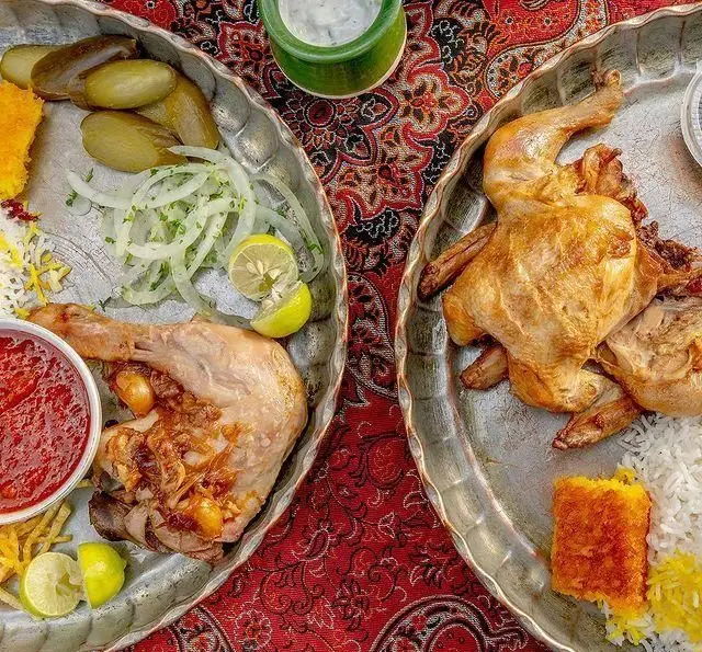 غذای اصیل رستوران گیلار: دو سینی شامل مرغ بریان کامل، ران مرغ، برنج زعفرانی، ته دیگ، پیاز، لیمو، خیارشور و سس گوجه. تجربه طعم بی‌نظیر.