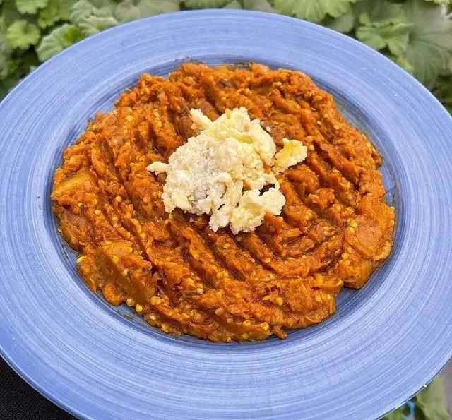 کشک بادمجان اصیل گیلانی رستوران گیلار در بشقاب آبی، با تزیین کشک، غذایی خوشمزه و سنتی برای لذت‌بردن.