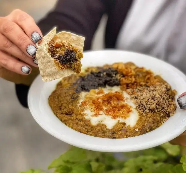 لذت تجربه طعم اصیل و غذای گیلانی در رستوران گیلار. این تصویر یک بشقاب کشک بادمجان یا حلیم بادمجان با تزئینات متنوع را نشان می‌دهد.