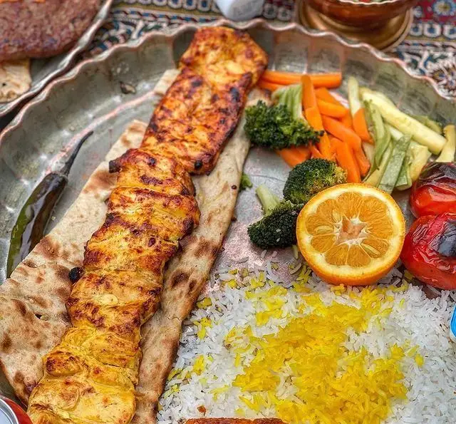 سینی زیبای جوجه کباب زعفرانی رستوران گیلار با برنج ایرانی، نان لواش، سبزیجات تازه کبابی، گوجه و پرتقال. طعم اصیل و لذیذ.