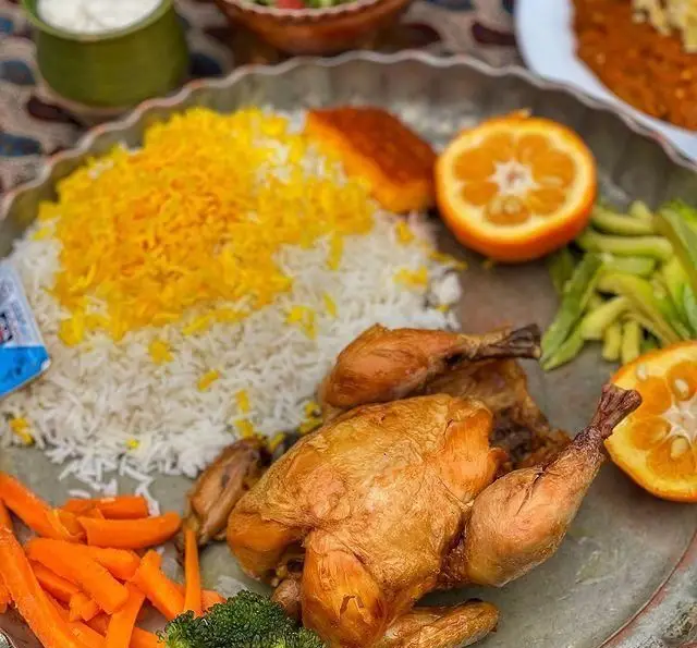 تصویر جذاب یک سینی غذای مجلل رستوران گیلار: مرغ بریان کامل، پلو زعفرانی معطر، سبزیجات تازه (هویج، بروکلی، لوبیا سبز) و پرتقال.