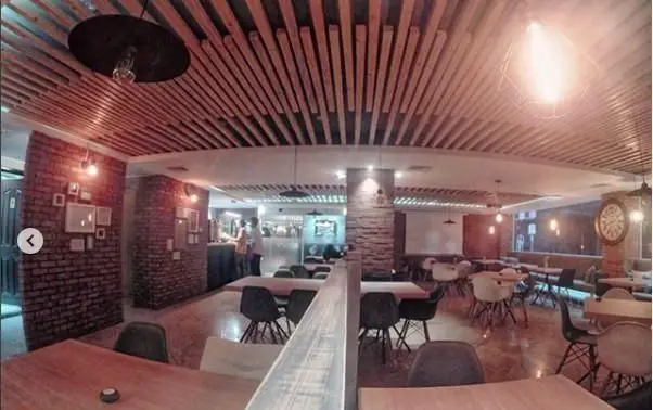 دکوراسیون داخلی کافه رستوران ویراک با سقف چوبی مدرن، دیوارهای آجری، میز و صندلی‌های شیک و نورپردازی گرم و دلنشین.