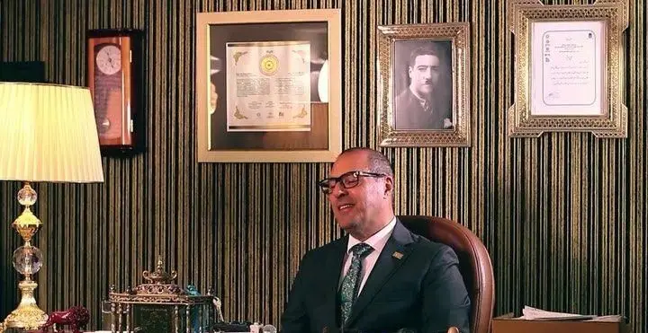 مدیر رستوران رفتاری در دفتر کار مجلل با دکوراسیون کلاسیک، تابلوهای دیواری و میز کار، بازتابی از اصالت و کیفیت این برند.