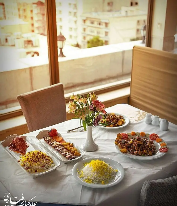 لذت یک وعده غذای سنتی ایرانی در رستوران رفتاری: کباب، برنج زعفرانی و خورش با دکوراسیون زیبا و چشم‌انداز خیره‌کننده شهر.