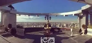 روف‌گاردن مجلل رستوران رفتاری با منظره خیره‌کننده شهر، فواره مرکزی، گلدان‌های زیبا و آسمان صاف، تجربه‌ای بی‌نظیر.