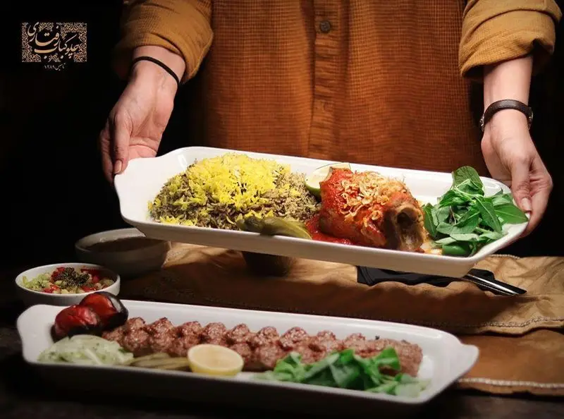 نمایی از سرو غذاهای اصیل ایرانی در رستوران رفتاری شامل باقالی پلو با ماهیچه و کباب کوبیده لذیذ با چیدمان زیبا و حرفه‌ای.